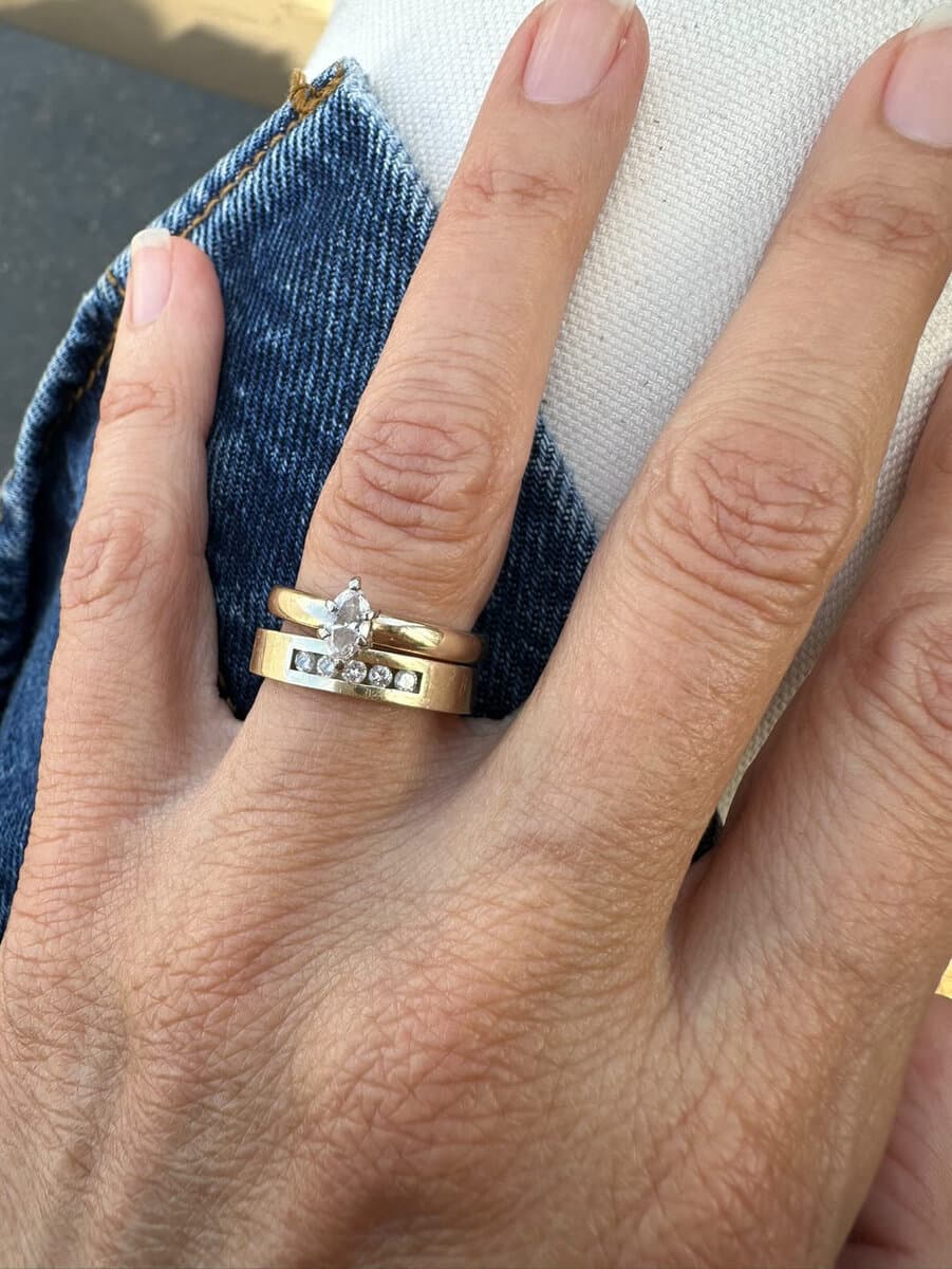Two hands wearing stacked gold bands by Sara Lundquist