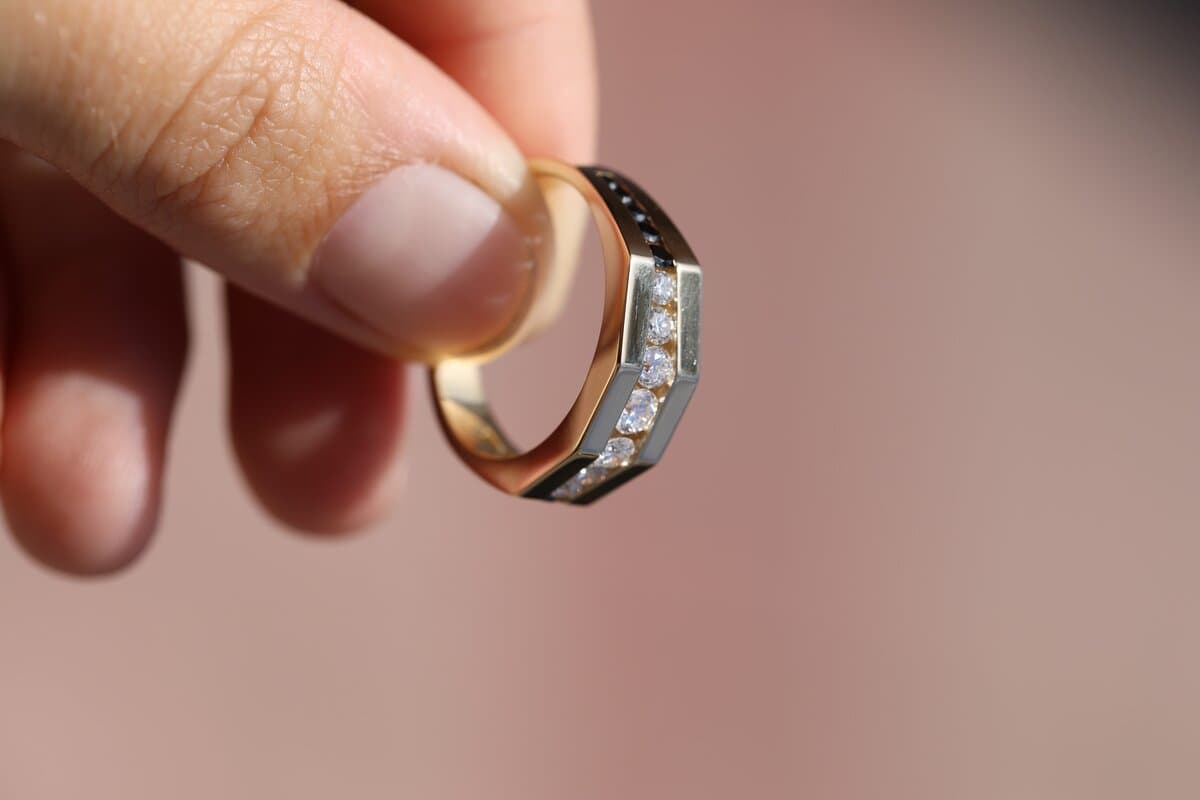A bevelled yellow gold band with channel-set diamonds, held between two fingers