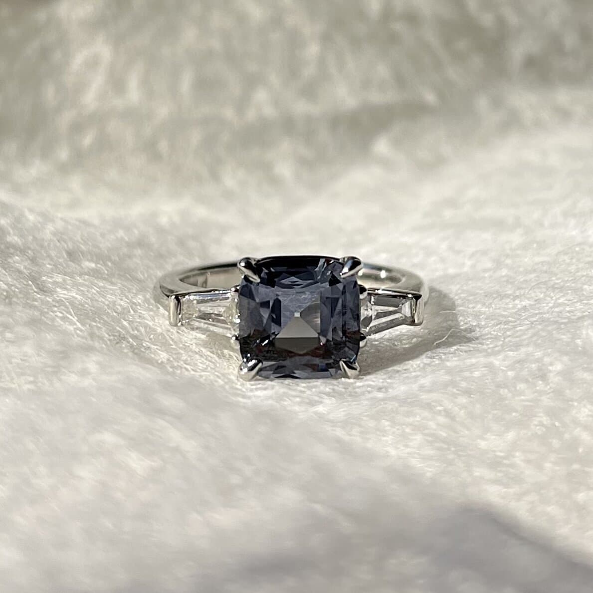 A cushion-cut gray-blue stone with tapered baguette sides, reset in a white-metal ring by Sara Lundquist