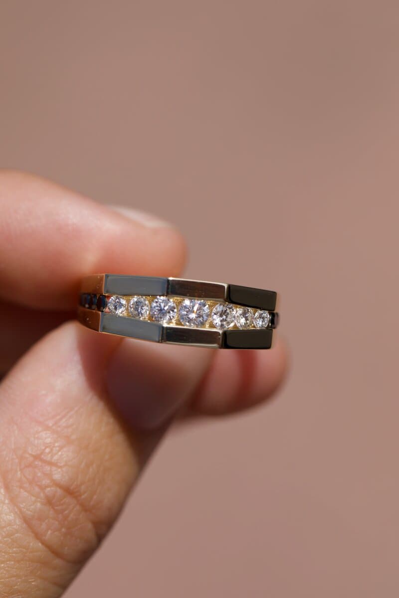 A channel-set diamond band held between a client’s fingers
