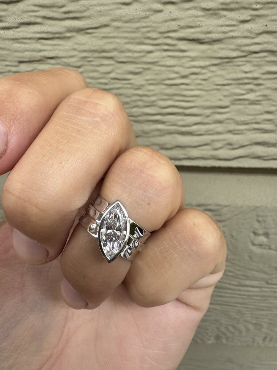 A marquise diamond in a white-metal bezel setting, worn on a hand