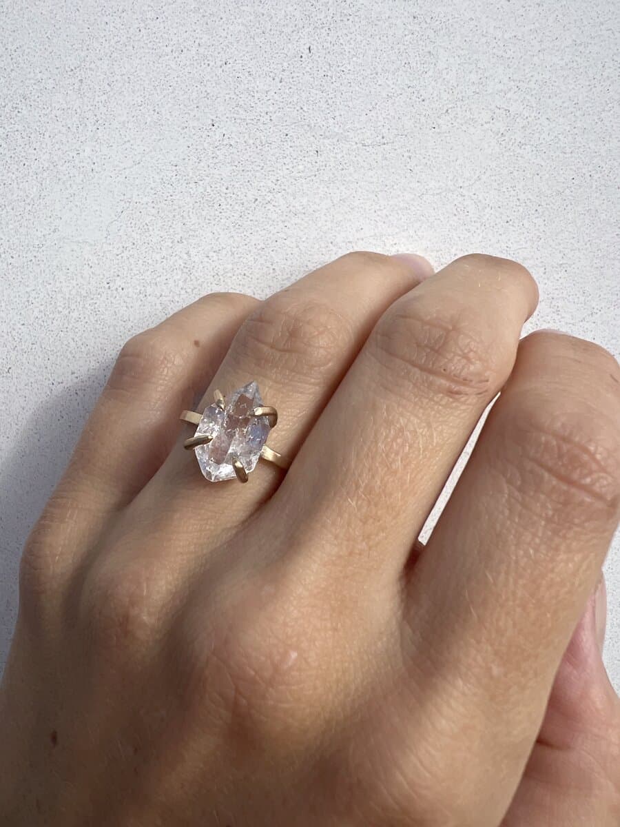 A hand wearing a six-prong oval diamond solitaire in yellow gold