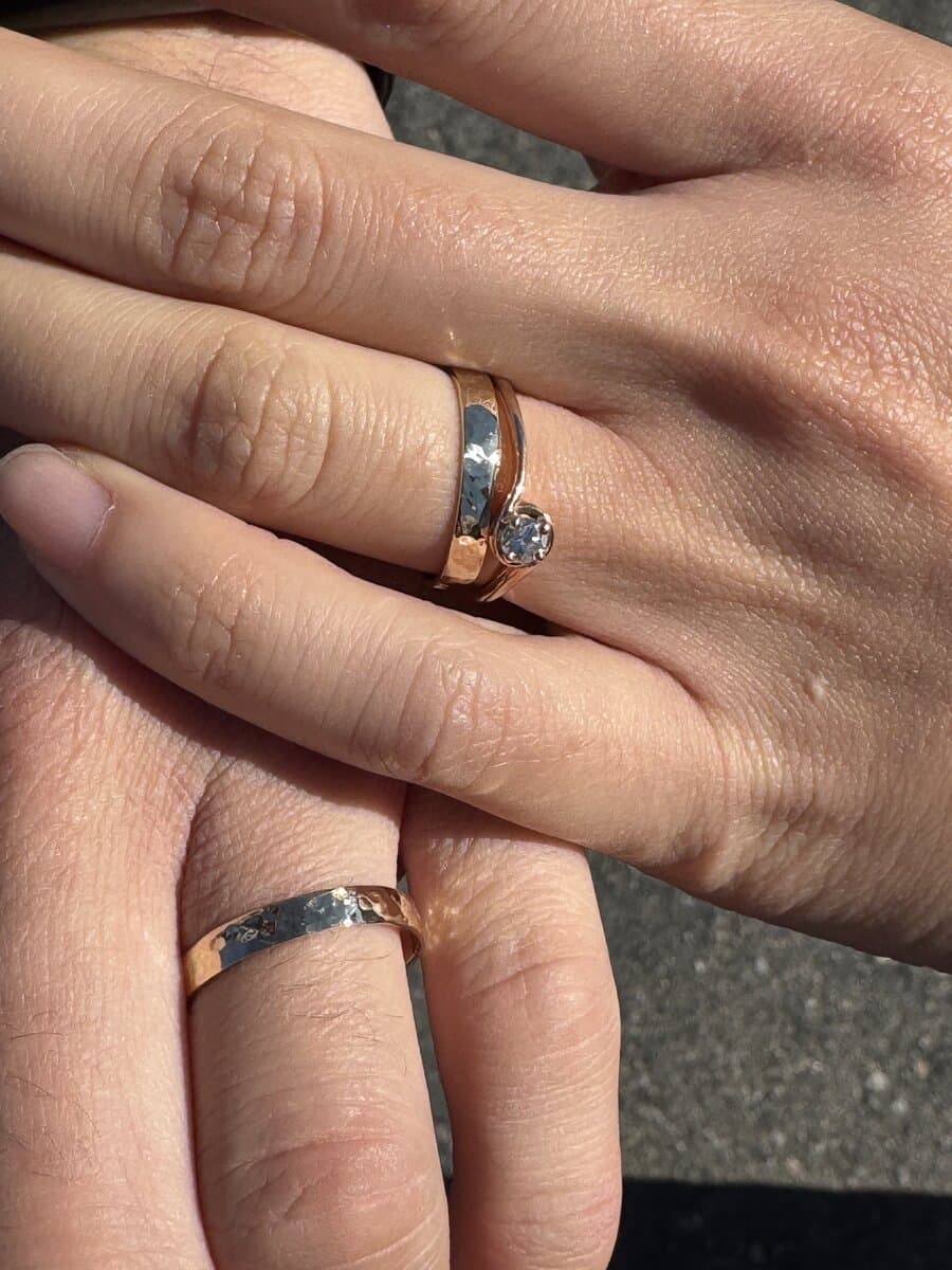 Two hands wearing gold bands made by Sara Lundquist