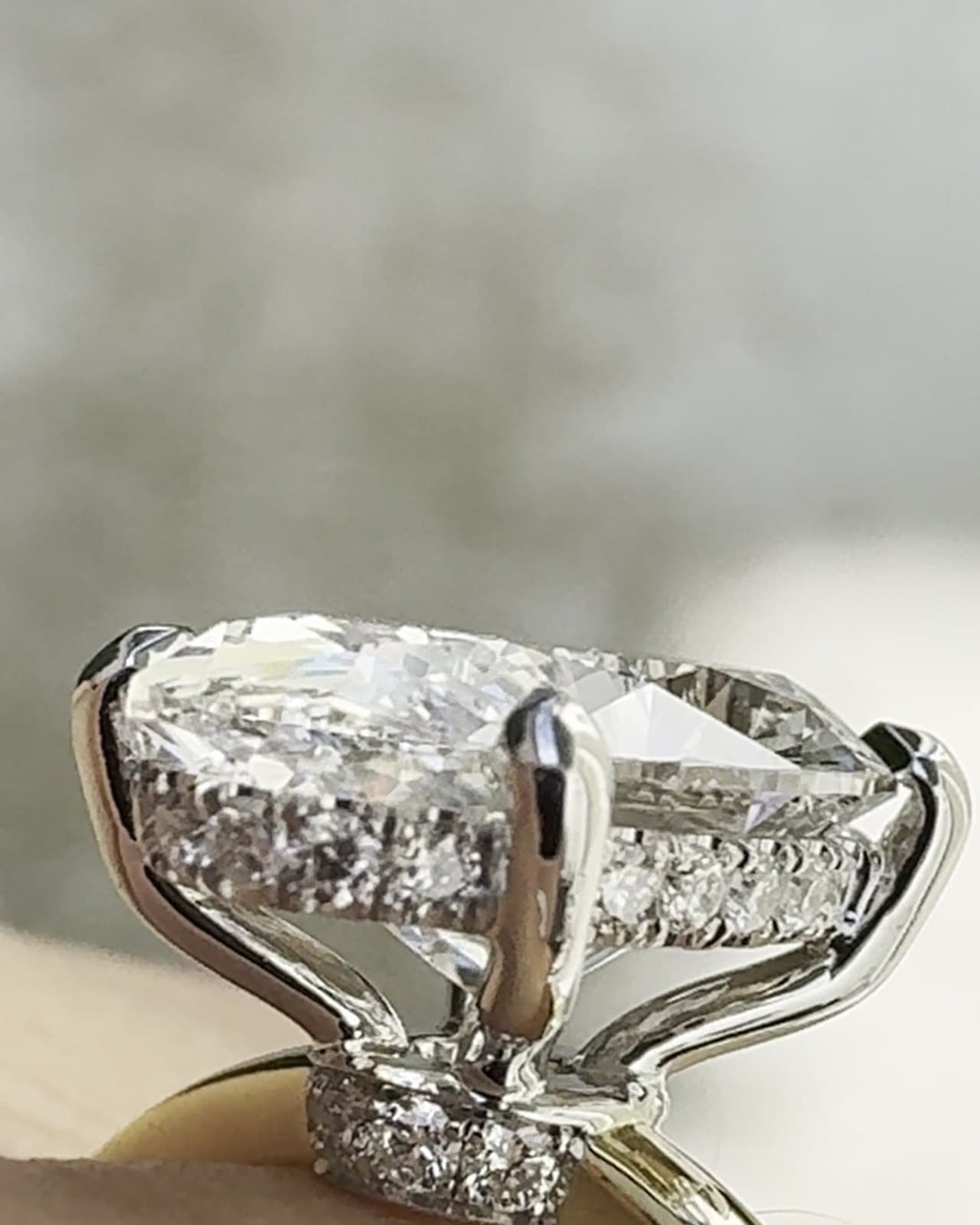 A close side view of a diamond ring with a hidden halo under the center stone and a yellow gold band