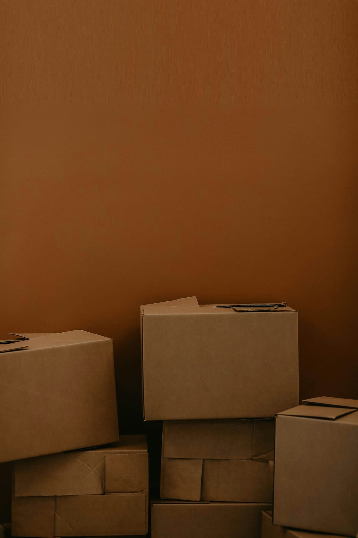 Plain cardboard shipping boxes stacked against a warm wall